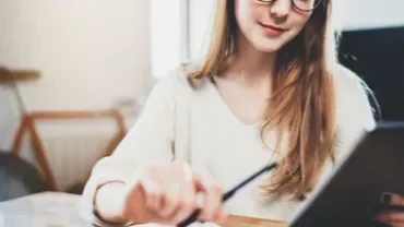 Mulher com óculos fazendo anotações digitalmente.