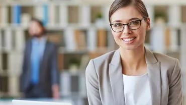 Mulher de óculos sorrindo em um escritório moderno.