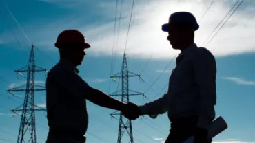 Silhueta de dois homens apertando as mãos em um campo de energia elétrica