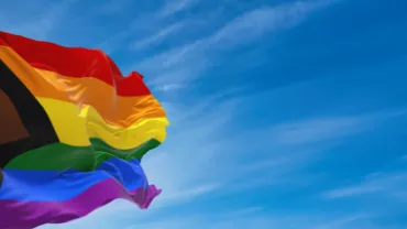 Bandeira LGBTQIAP voando no céu azul 
