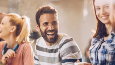 Homem sorrindo enquanto trabalho com o resto do time