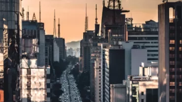 Vista da Avenida Paulista ao entardecer com edifícios modernos.