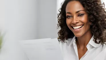 Mulher negra de camisa branca trabalhando com um papel em mãos