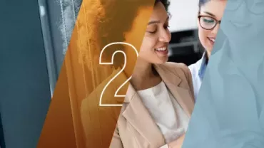 Duas mulheres sorrindo enquanto discutem algo em um escritório.