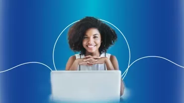 Mulher sorridente diante de um laptop com fundo azul.