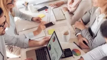 Pessoas discutindo gráficos em uma reunião de trabalho.