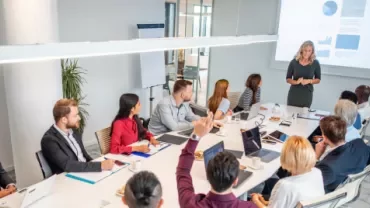 Homens e mulheres em uma sala de reunião sentados e conversando