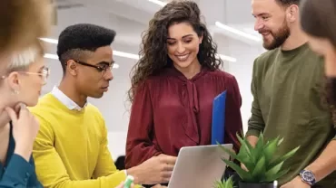 Grupo de pessoas conversando em volta de uma mesa de trabalho.