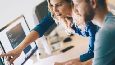 Dois colegas trabalhando juntos em códigos no computador.