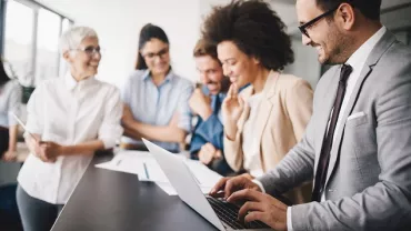 Equipe diversa discutindo sobre computador no escritório.