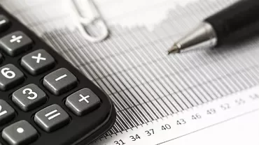Calculadora e caneta sobre gráfico em papel.