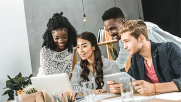 Grupo de jovens discutindo projeto em um laptop.