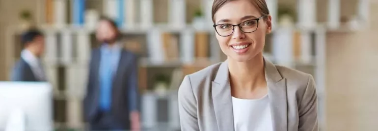 Mulher de óculos sorrindo em um escritório moderno.