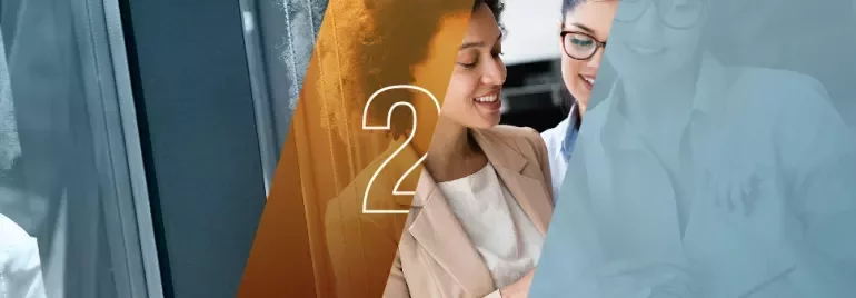 Duas mulheres sorrindo enquanto discutem algo em um escritório.