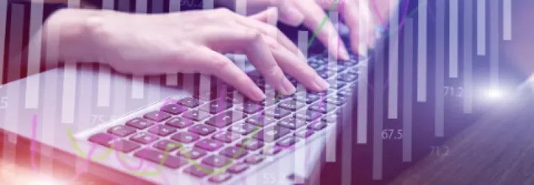 Pessoa digitando em teclado de computador com gráficos ao fundo.