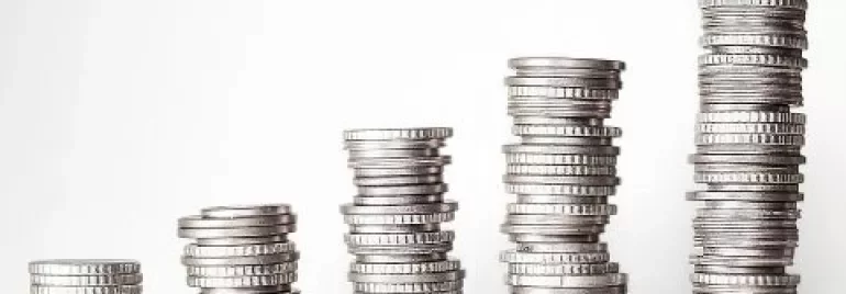 Pilhas crescentes de moedas ilustrando aumento financeiro.
