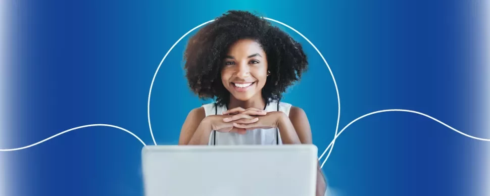 Mulher sorridente diante de um laptop com fundo azul.