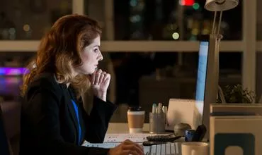 Mulher concentrada trabalhando no computador à noite.