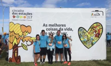 Grupo de pessoas posando em frente a um banner do evento Circuito das Estações.