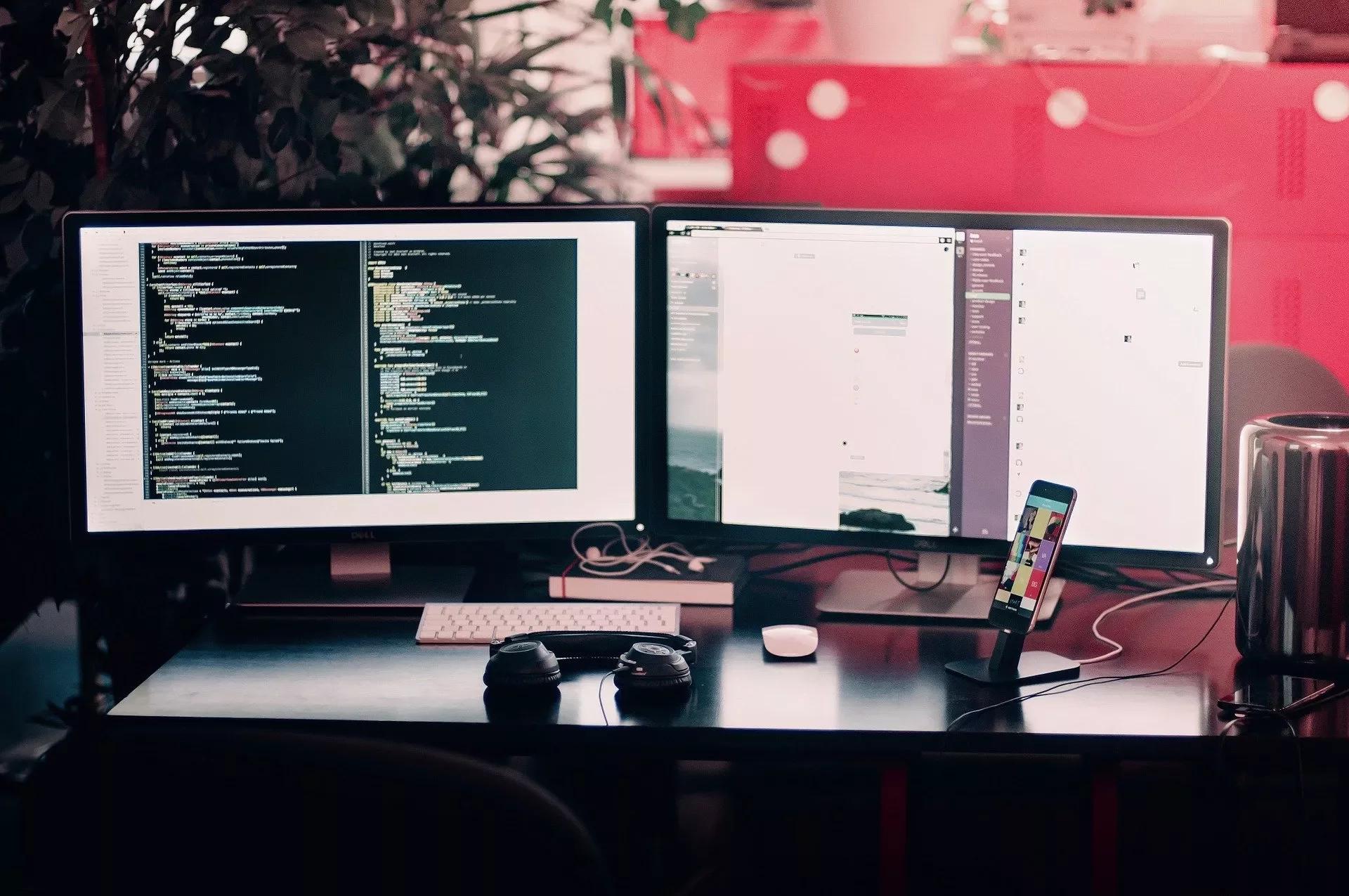 Estação de trabalho com dois monitores exibindo código de programação.