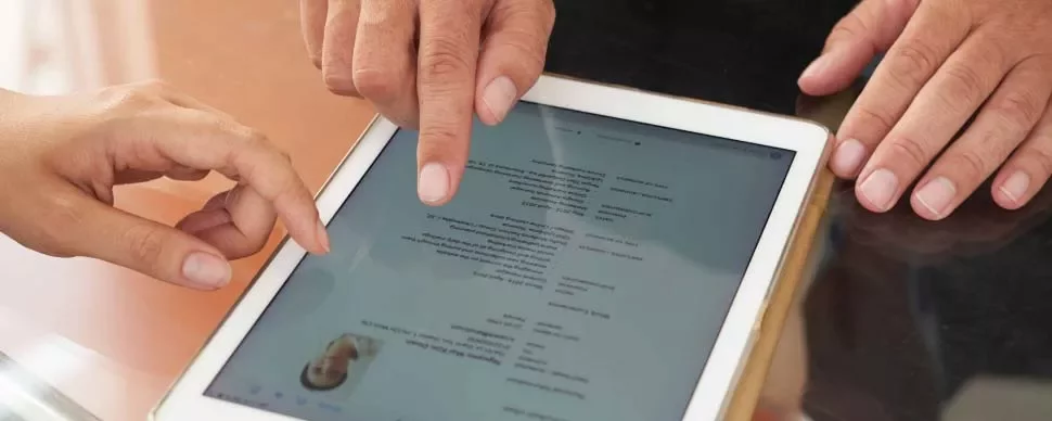 Duas pessoas revisando curriculum em um tablet.