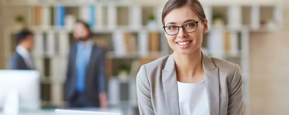 Mulher de óculos sorrindo em um escritório moderno.