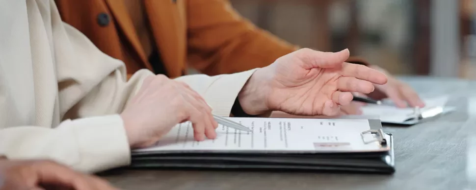 Mãos gesticulando em cima de um documento sobre a mesa.