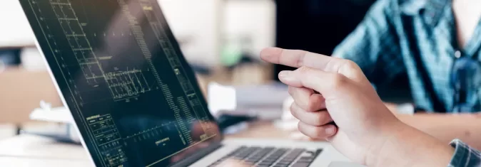 Pessoa apontando para tela de computador com gráficos.