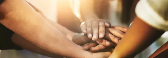 Mãos juntas simbolizando união e trabalho em equipe.