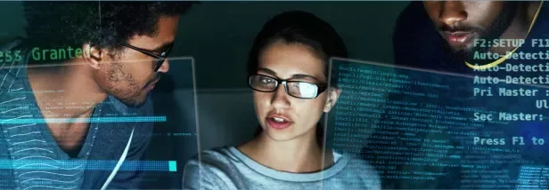 Três pessoas analisando códigos de computador em um escritório.