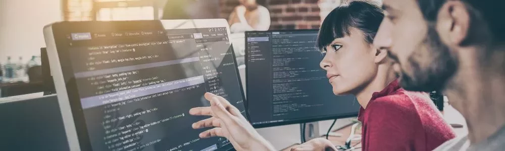 Dois programadores trabalhando em um projeto de código em monitores.