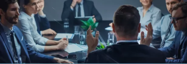 Executivos em reunião ao redor de uma mesa de conferência, discutindo assuntos importantes.