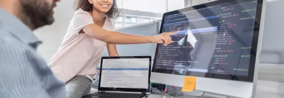 Pessoa apontando para uma tela com código de programação.