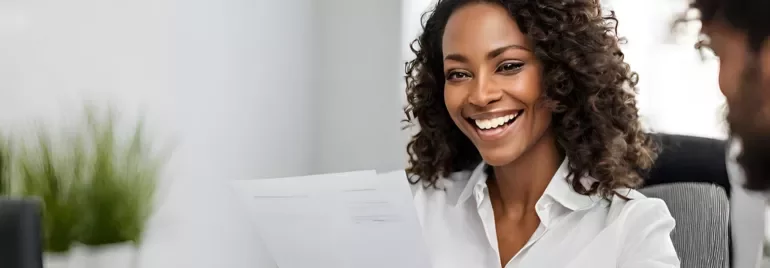 Mulher sorrindo enquanto segura documentos em um escritório.
