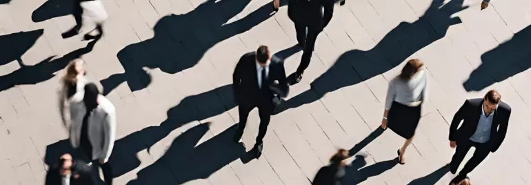 Vista aérea de pessoas caminhando na rua com longas sombras.