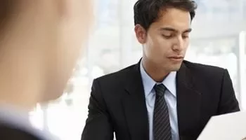 Homem de terno olhando para documento em escritório.