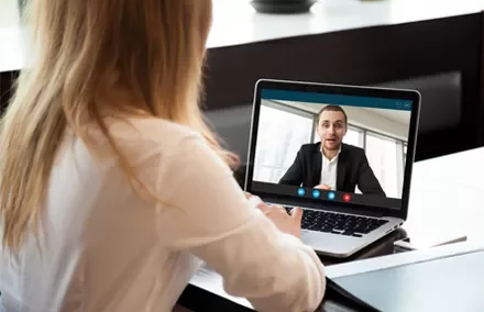 Mulher em chamada de vídeo com homem em laptop.