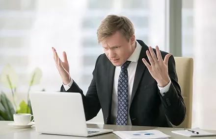 Homem frustrado olhando para o laptop no escritório.