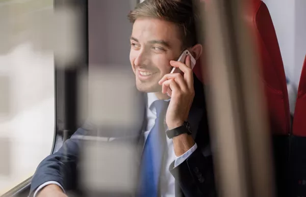 Homem sorridente falando ao celular em um trem