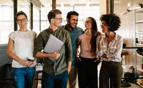 Grupo de colegas sorrindo em um escritório.