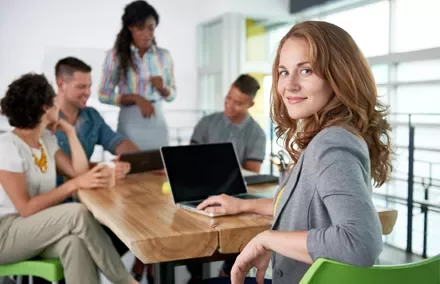 Mulher sorrindo em uma reunião de equipe.