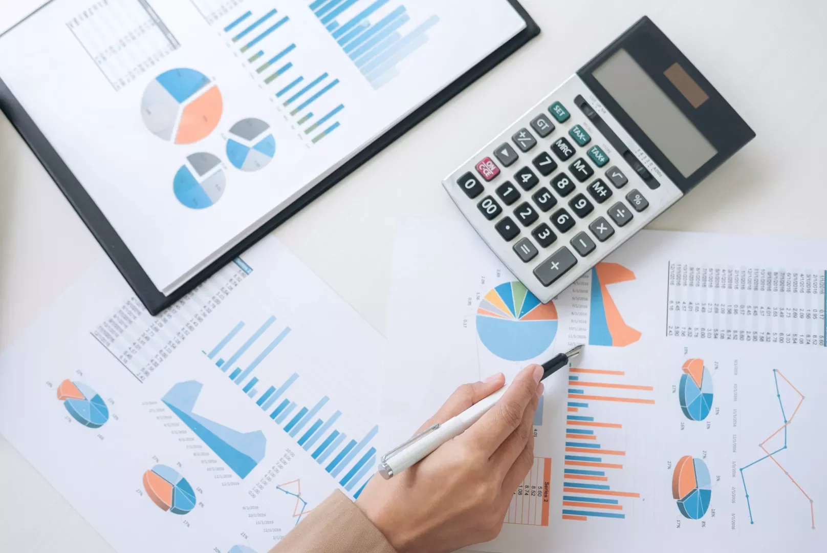 Pessoa analisando gráficos e calculadora.