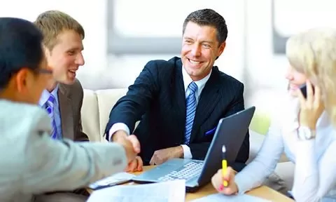 Grupo de pessoas em reunião, apertando as mãos.