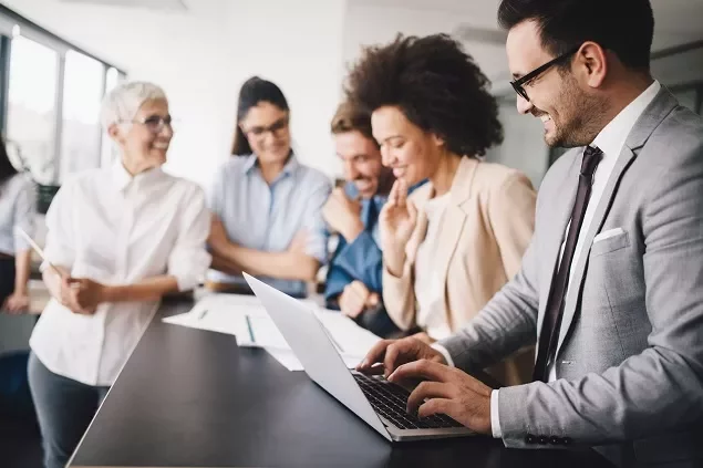 Equipe diversa discutindo sobre computador no escritório.