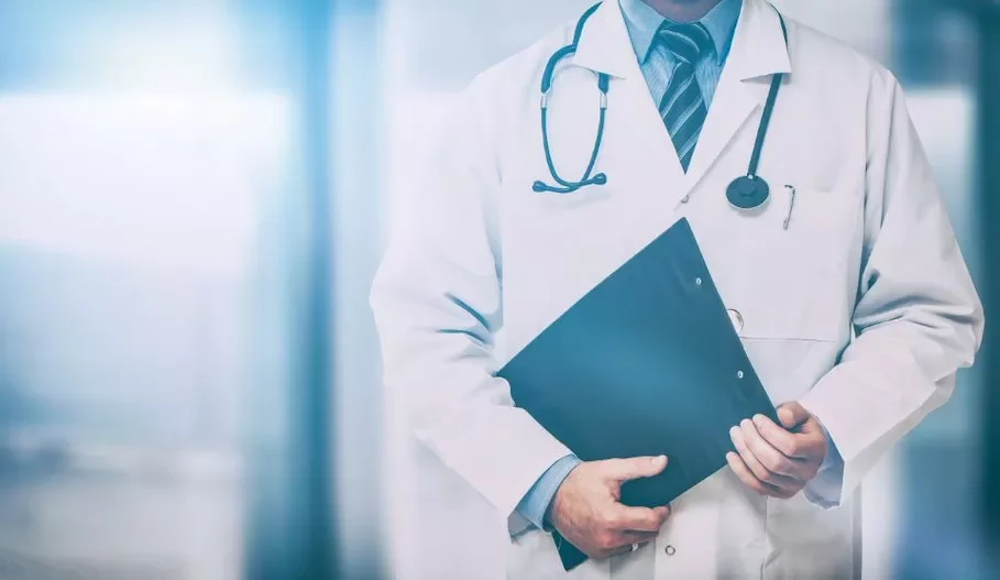 Médico com jaleco branco e estetoscópio, segurando uma prancheta.