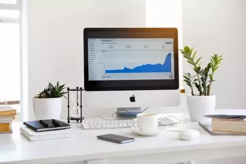 Computador em uma mesa de escritório com gráficos na tela.
