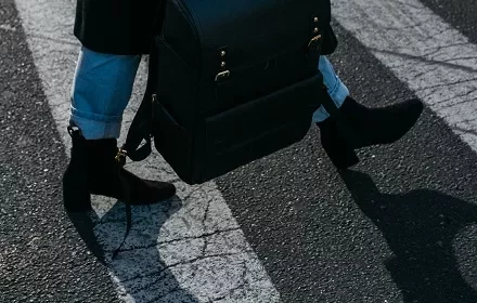 Pessoa caminhando na faixa de pedestres com botas pretas.