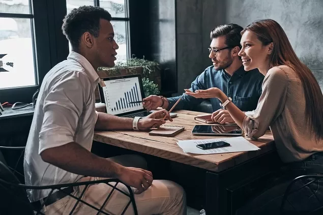 Três pessoas discutindo gráficos em um escritório.