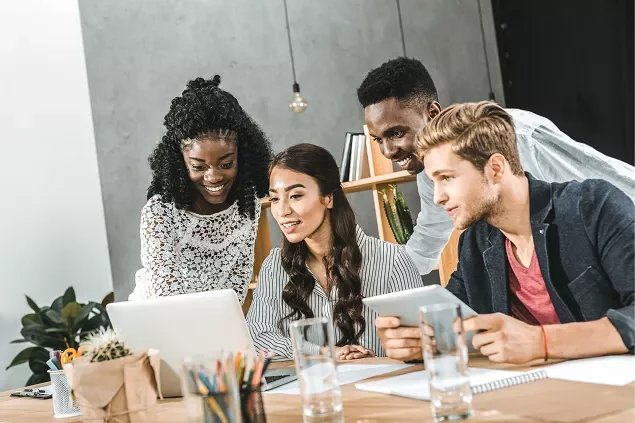 Grupo de jovens discutindo projeto em um laptop.